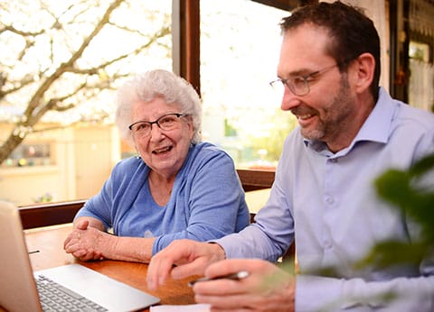 Adults Support Coordination - image of adult man helping elderly senior woman with computer - Encompass Community Supports