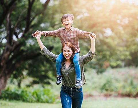 Child and Adolescent Behavioral Health Supports Coordination - mother carrying child on shoulders playfully - Encompass Community Supports