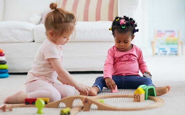 Infant and Toddler Supports - image of cute toddler baby girls playing with blocks - Encompass Community Supports