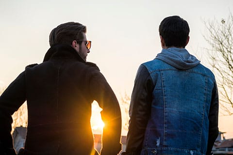 Peer Recovery Supports - image of two adult men talking with sun shining on horizon - Encompass Community Supports