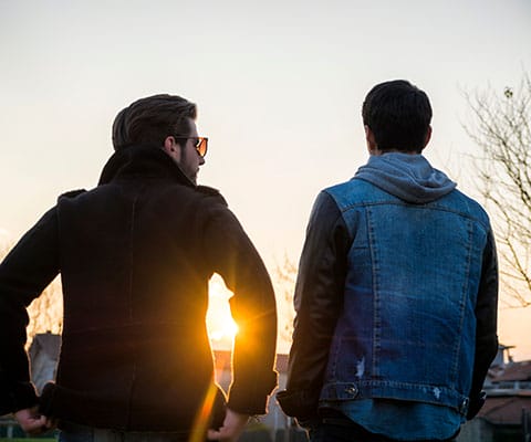 Peer Recovery Supports - image of two adult men talking with sun shining on horizon - Encompass Community Supports