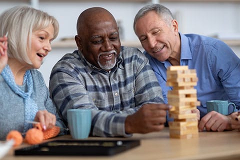 Social Activities for aging adults - image of group of older friends playing games together - Encompass Community Supports